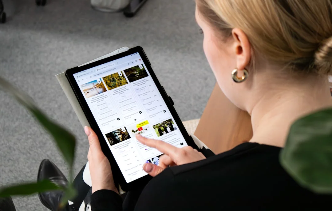 Osoba uvnitř analyzuje burzovní data pomocí chytrého telefonu a notebooku.